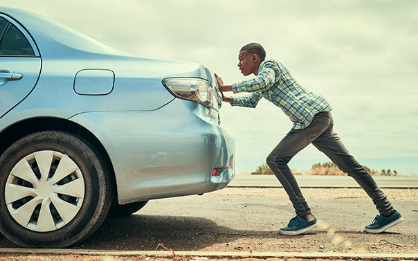 man pushing car on roadside